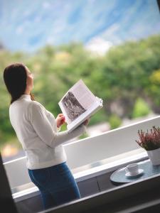une femme lit un livre dans une fenêtre dans l'établissement Trolltunga Aparthotel, à Tyssedal