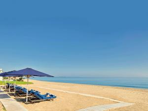 una playa con sillas y sombrillas azules y el océano en Sofitel Tamuda Bay Beach And Spa, en M'diq