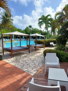 a patio with a pool and tables and chairs at Au petit Régal in Sainte-Anne