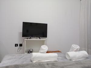 a bedroom with towels on a bed with a flat screen tv at VASO'S APPARTMENTS A in Missolonghi