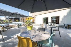 a patio with tables and chairs and umbrellas at Brit Hotel Angers Parc Expo - L'Acropole in Saint-Sylvain-dʼAnjou