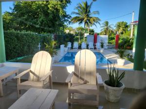 two white chairs and a table and a pool at Villa sonia in Juan Barón