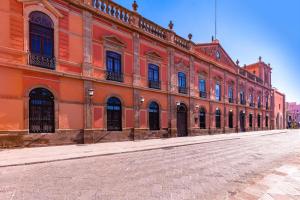 un grand bâtiment orange avec une rue en face dans l'établissement NH San Luis Potosí, à San Luis Potosí