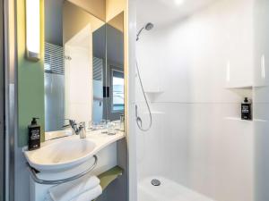 y baño blanco con lavabo y ducha. en ibis budget Frankfurt City Ost, en Frankfurt