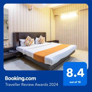 ボーパールにあるFabHotel Shree Regencyのオレンジと白の枕が付いたベッドが備わるホテルルームです。