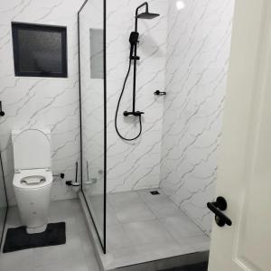 biała łazienka z prysznicem i toaletą w obiekcie The KWASU Apartments w mieście Chipata