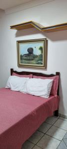 uma cama num quarto com uma fotografia na parede em SUÍTE Alfa em Vila Velha