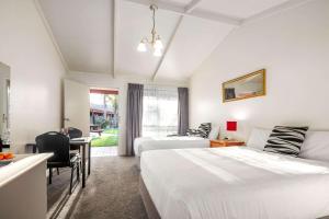 a hotel room with two beds and a desk and a table at Quality Hotel Lakeside in Bendigo