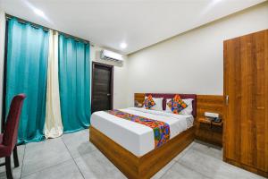 Schlafzimmer mit einem großen Bett und blauen Vorhängen in der Unterkunft Via HC Dream Majestic in Mohali