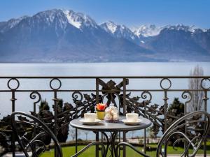 una mesa con 2 tazas en un balcón con montañas en Fairmont Le Montreux Palace, en Montreux