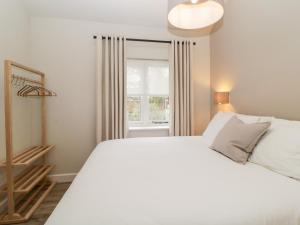 a bedroom with a white bed and a window at Lower Marsh Barns in Exeter