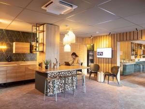 a woman sitting at a table in a kitchen at ibis Styles Les Houches Chamonix in Les Houches