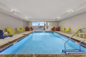 Home2 Suites By Hilton Cedar Rapids Westdale في سيدار رابيدز: حمام سباحة مع كراسي وكراسي ملونة في غرفة في الفندق