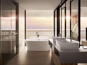 une salle de bain avec deux lavabos et une baignoire dans l'établissement Novotel Sihanoukville Holiday Resort, à Sihanoukville