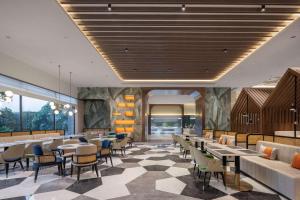 ein Restaurant mit Tischen und Stühlen und eine Lobby in der Unterkunft Hilton Garden Inn Jiangmen Xinhui in Jiangmen
