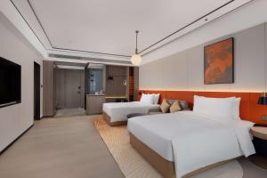 Hilton Garden Inn Jiangmen Xinhui في جيانغمن: غرفه فندقيه سريرين وتلفزيون
