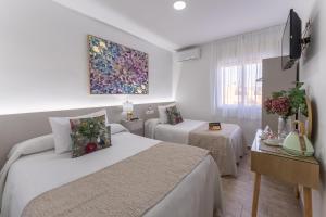 een hotelkamer met 2 bedden en een televisie bij Urban Rooms B&R in Málaga