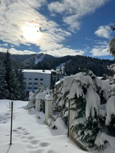 una valla cubierta de nieve con árboles y montañas en Apartament Bonton Predeal en Predeal