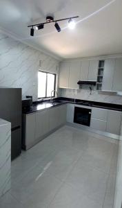 a large kitchen with white cabinets and a window at The KWASU Apartments in Chipata