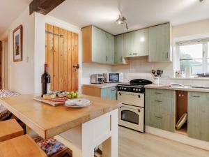 a kitchen with green cabinets and a wooden table at 2 Bed in Brecon 51153 in Llandefalle