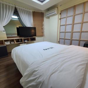 Schlafzimmer mit einem weißen Bett und einem TV in der Unterkunft Danggum Stay in Suncheon