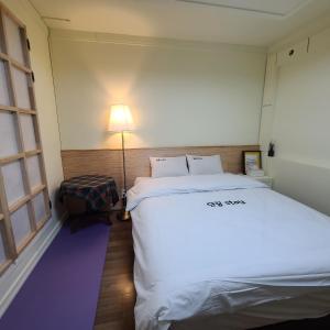 ein kleines Zimmer mit einem Bett und einer Lampe in der Unterkunft Danggum Stay in Suncheon