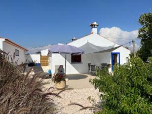 een wit huis met een paraplu ervoor bij Quinta Samor in Aljezur