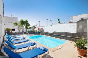 una piscina con tumbonas azules junto a un edificio en Villa Muñoz, en Puerto del Carmen