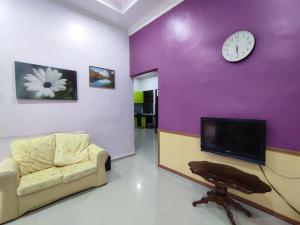 ein Wohnzimmer mit einem Sofa und einer Uhr an der Wand in der Unterkunft NikNa Homestay Batu Rakit - WIFI in Kampong Ru Tujoh