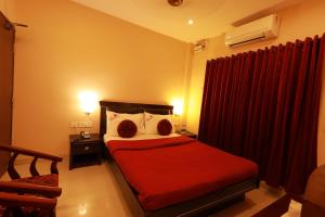 a bedroom with a red bed and a red curtain at Hotel Nakshatra Inn VL Tuticorin in Tuticorin