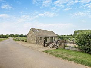 a barn with a fence next to a road at 1 Bed in Cirencester 57684 in Kemble