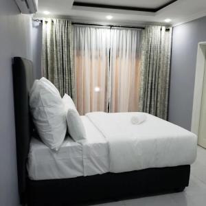 a bed with white sheets and pillows in a bedroom at The KWASU Apartments in Chipata