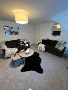 a living room with a black couch and a table at The Harbour Cottage in Peterhead