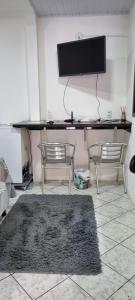 2 sillas y escritorio con TV en la pared en SUÍTE ÔMEGA, en Vila Velha