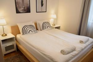 een slaapkamer met een bed met witte lakens en 2 lampen bij Peony Káldy Apartman Free Garage under the house in Boedapest