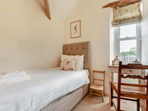 a bedroom with a bed and a chair and a window at 2 Bed in Grange Over Sands 73544 in Grange Over Sands