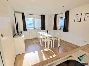 a white dining room with a table and chairs at frisch modernisiertes Apartment in Altdorf