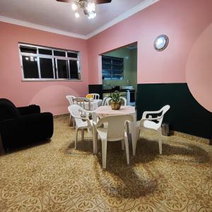 uma sala de jantar com paredes cor-de-rosa, uma mesa e cadeiras em Casa de Praia Boqueirão em Santos