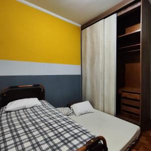 um quarto com uma cama e uma parede amarela e azul em Casa de Praia Boqueirão em Santos