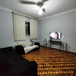 uma sala de estar com um sofá e uma televisão em Casa de Praia Boqueirão em Santos