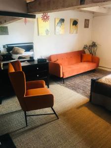 - un salon avec un canapé orange et un bureau dans l'établissement Mirepoix Labyrinthe chambre avec salle de bain et lit 180 cm, à Mirepoix