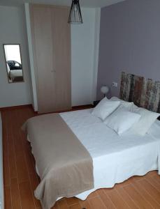 een slaapkamer met een groot wit bed met witte kussens bij Apartamento Camiño dos Faros in Malpica