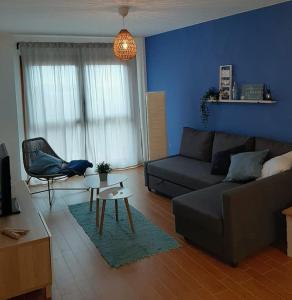 een woonkamer met een bank en een blauwe muur bij Apartamento Camiño dos Faros in Malpica