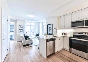een keuken met witte kasten en een fornuis met oven bij Luxe Toronto Townhome, Rooftop Terrace, Parking in Toronto