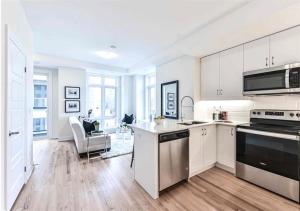 a kitchen with white cabinets and a stove top oven at Luxe Toronto Townhome, Rooftop Terrace, Parking in Toronto