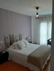 een slaapkamer met een groot bed met witte lakens en kussens bij Apartamento Camiño dos Faros in Malpica