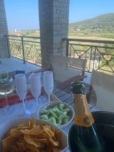 uma mesa com uma garrafa de champanhe, batatas fritas e taças de vinho em Villa Vlamari em Vathý