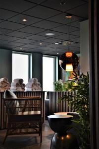 a room with a chair and a table and windows at ProfilHotels Halmstad Plaza in Halmstad