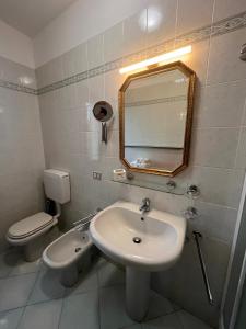 a bathroom with a sink and a toilet and a mirror at TerrazzaVistaMare, Piscina, CampoDaTennis in Sanremo