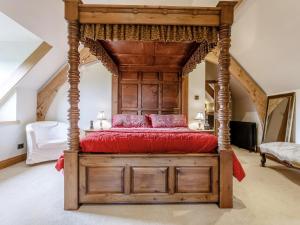 Schlafzimmer mit einem hölzernen Himmelbett und roten Kissen in der Unterkunft 4 Bed in Latchley 77480 in Sydenham Damerel